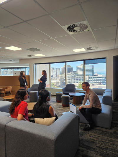 Five people in an open office space with modular furniture and large window views.