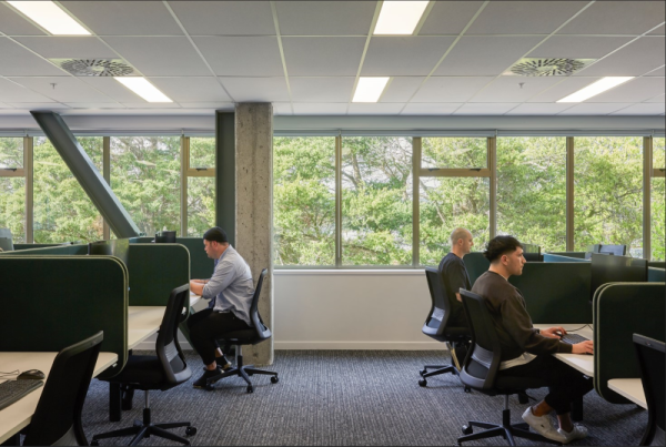 Three people focused on their work at desks in an open office space.